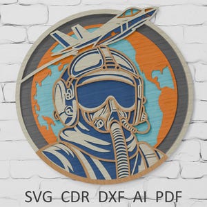 May include: A circular wooden artwork depicting a pilot and a jet. The design uses blue, orange, and light wood colours. The pilot's helmet and the plane are the focal points. The text "SVG CDR DXF AI PDF" is at the bottom of the artwork.