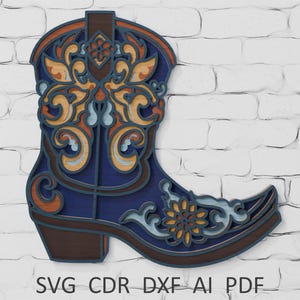 May include: A layered wooden cowboy boot in shades of blue, brown, and orange, with detailed floral and scrollwork designs. The boot is displayed against a white brick wall. The text "SVG CDR DXF AI PDF" is at the bottom.