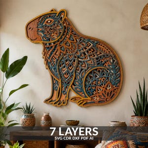 May include: A multi-layered wooden wall art piece shaped like a capybara, featuring intricate laser-cut mandala patterns in shades of natural wood, teal, and dark blue. The artwork consists of 7 layers, as indicated by the text 7 LAYERS SVG CDR DXF PDF AI.