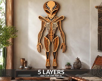 May include: A multi-layered wooden wall art piece depicting a stylized alien figure with an elongated head and skeletal body structure. The design features five distinct layers of wood in varying shades of brown, creating depth and texture.