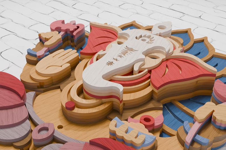 May include: A multi-layered wooden wall art piece depicting the deity Ganesha. The design features stacked laser-cut wood panels in shades of natural wood, red, and blue, forming the elephant head, lotus petals, and symbolic hand gestures.