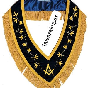 Può includere: Un collare cerimoniale con base in velluto blu navy, disegni floreali ricamati in oro e frange dorate. Il collare ha una fodera in raso blu e un simbolo massonico nella parte inferiore. Il testo "Taiessaimpex" è visibile.
