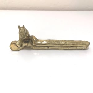 May include: A brass nutcracker featuring a sculpted fox figure integrated into the handle design. The metal tool has a textured, aged finish with a hinged mechanism for cracking nuts, showcasing a long, slender body and a detailed fox head.