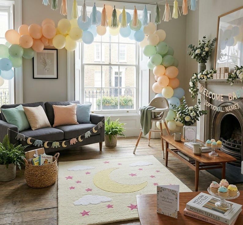 May include: A room decorated for a baby shower with pastel balloons, a gray sofa, and a rug with a moon and star design. A high chair and a wooden coffee table are also present. A banner reads "Welcome Baby".