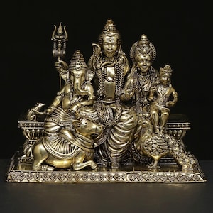 Può includere: Una statua color oro raffigurante una famiglia indù. Le figure centrali sono sedute, con un bambino e un pavone nelle vicinanze. Ganesha è a sinistra e un toro è alla base. La statua è su una base decorativa.