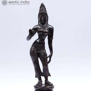 May include: A bronze statue of a slender female figure, standing on a lotus-shaped base. The figure is adorned with detailed jewelry and a headdress. The statue has a dark, aged patina, and the figure's pose suggests a graceful movement.