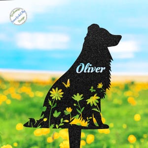 May include: Black metal garden stake shaped like a dog, with the name "Oliver" in blue script. The dog silhouette features floral and butterfly cutouts. The background shows a field of yellow flowers and a blue sky.