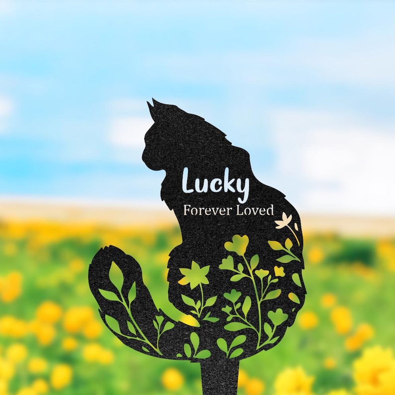 May include: A black metal garden stake shaped like a sitting cat with a cutout floral design. The text "Lucky" and "Forever Loved" is printed in white on the cat's body. The design features intricate leaf and flower patterns throughout.