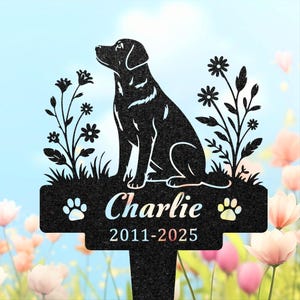 May include: A black metal garden stake featuring a silhouette of a sitting dog flanked by wildflowers. The center plaque displays the name Charlie and the years 2011-2025, accented by two paw print icons on either side of the name.