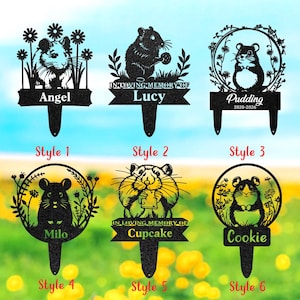 Könnte beinhalten: Schwarze Metall-Gartenstecker mit Hamster-Designs. Jeder Stecker hat eine andere Hamster-Illustration, mit Namen wie "Angel", "Lucy", "Pudding", "Milo", "Cupcake" und "Cookie". Einige Stecker enthalten den Text "In Loving Memory Of".
