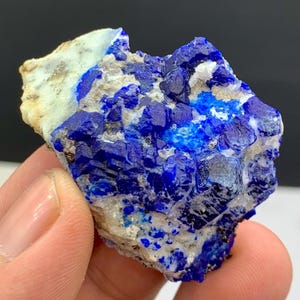 Puede incluir: Una taza de cerámica blanca con un asa negra y el texto "But First, Coffee" en negro, con una fuente de estilo manuscrito. La taza está sobre una superficie blanca.