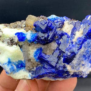 Puede incluir: Un vibrante espécimen mineral con estructuras cristalinas de color azul intenso contrastadas con una matriz de roca blanquecina y gris. El espécimen muestra una llamativa exhibición de color y textura, ideal para coleccionistas.