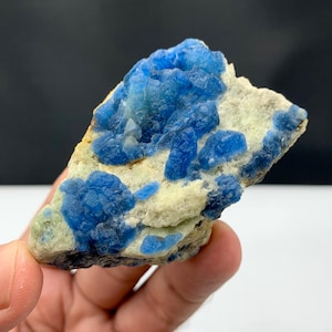 Puede incluir: Un vibrante espécimen mineral azul con formaciones cristalinas. El mineral es de un azul profundo y saturado, contrastando con la matriz blanquecina. La textura rugosa y natural de la piedra es visible, mostrando sus orígenes geológicos. Una pieza única para coleccionistas.