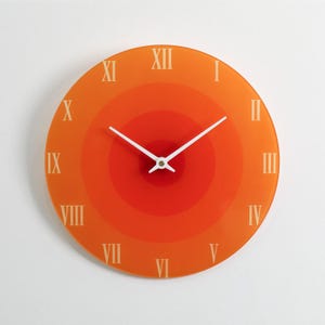 May include: A circular orange wall clock with a concentric design. The clock face has white Roman numerals and white hands. This decorative clock is a stylish addition to any home.