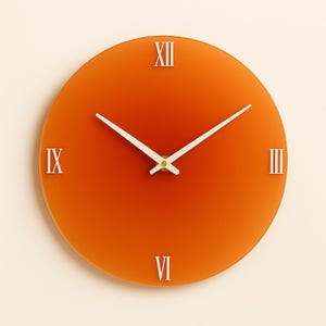 May include: Round orange wall clock with white hands and Roman numeral hour markers. The clock face is a solid orange color, and the hands are white. The clock is a simple, modern design.