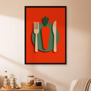 May include: A framed art print with a minimalist design. It features a carrot, fork, and knife arrangement. The carrot is orange, set against a green circle, with a red background. The fork and knife are beige.