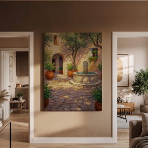 May include: A framed canvas print showing a sunlit courtyard scene. The artwork features a stone fountain, potted plants, and an arched doorway. The colour palette includes warm tones of beige, brown, and green, creating a serene atmosphere.