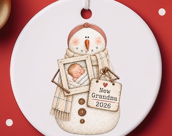 Adorno fotográfico de cerámica para la nueva abuela 2026: muñeco de nieve sosteniendo a un bebé. Ideal para regalos o para rellenar calcetines navideños.