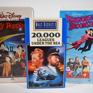 May include: Three vintage VHS tapes featuring Disney movies: "Mary Poppins", "20,000 Leagues Under the Sea", and "Bedknobs and Broomsticks". The tapes have colorful artwork and text, including the Disney logo and movie titles. The tapes are in their original packaging.
