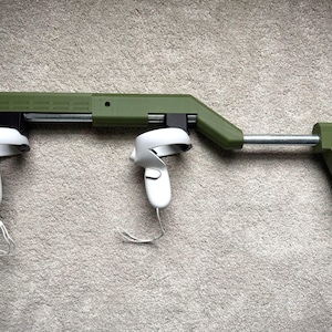 May include: A green and black VR controller gun stock with two white VR controllers attached. The stock has a metal barrel and a green buttstock. The controllers are connected with white cords.
