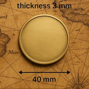 May include: A circular, brushed gold-tone metal coin or disc with a raised outer rim. The object features a diameter of 40 mm and a thickness of 3 mm, as indicated by the text and measurement arrows printed directly on the image.
