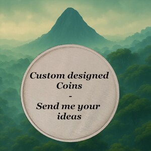 May include: A circular silver-toned coin featuring the black text Custom designed Coins - Send me your ideas centered on its surface. The coin is positioned against a backdrop of a green mountain landscape with dense forest foliage.