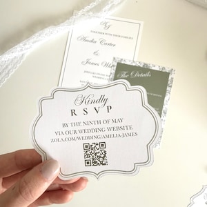 Puede incluir: Juego de invitaciones de boda con una tarjeta RSVP blanca con un borde decorativo y el texto "Kindly RSVP". Las tarjetas adicionales incluyen detalles de la boda y nombres. Se incluye un código QR. Una cinta de encaje blanco está en el fondo.