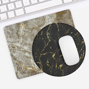 May include: A computer mouse and two mouse mats. One rectangular mat has a grey marble design with gold veining. The other is a round black mat with gold veining. A white mouse rests on the black mat.