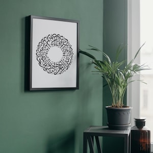 May include: A framed black and white print featuring intricate Arabic calligraphy in a circular design. The artwork is displayed on a green wall, adding a touch of elegance to the space. The frame is black.