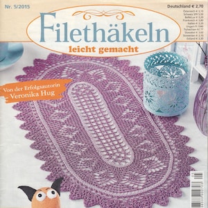 以下が含まれることがあります： 紫色の縁取りのある白いレースの楕円形のコースターが載っている雑誌の表紙。雑誌のタイトルは「Filethäkeln leicht gemacht」、サブタイトルは「Von der Erfolgsautorin Veronika Hug」です。