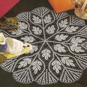 May include: White crocheted doily with a delicate floral design. The doily is circular and has a scalloped edge.
