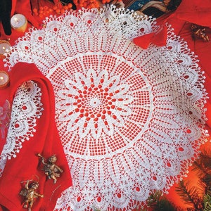 May include: White crocheted doily with a delicate floral design. The doily is laid on a red surface with Christmas decorations.