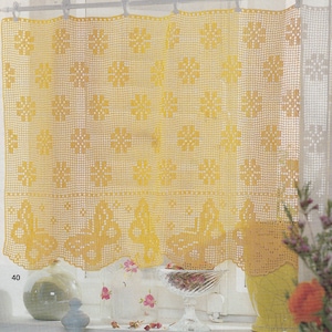 Può includere: Tende in crochet gialle con un motivo a fiocco di neve appese a una finestra. Le tende sono realizzate con un design delicato e traforato.