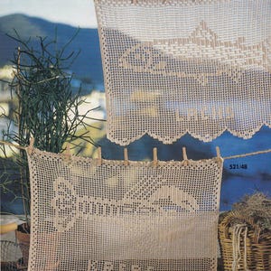 May include: Two rectangular beige crochet panels hanging from a clothesline. The top panel features a fish motif with the text "LACHS" at the bottom. The bottom panel displays a lobster motif with the text "KREBS" and the number "521/48" visible.