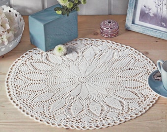 May include: White crocheted doily with a delicate floral pattern. The doily is round and has a diameter of approximately 12 inches.