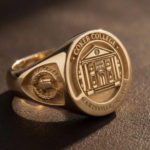 May include: A gold signet ring with the words "COKER COLLEGE" encircling a detailed illustration of a building. The ring also features the text "HARTSVILLE, SC. 1908". A smaller emblem is on the side of the ring.