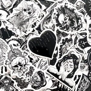 May include: A collection of black and white stickers with gothic and occult themes. Designs include skulls, hearts, demons, and other dark imagery. The stickers are of various shapes and sizes, with intricate details.
