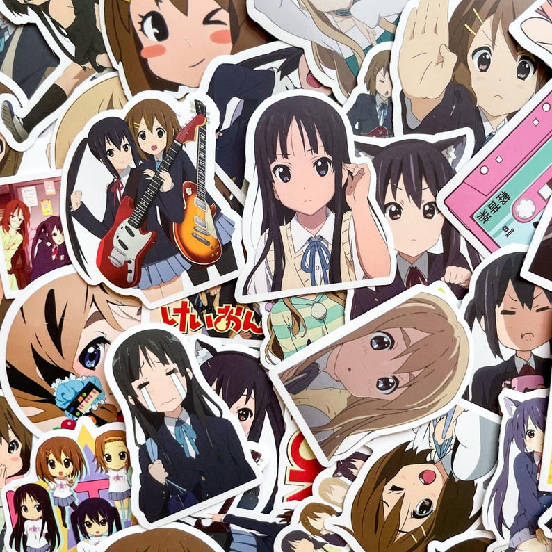 Pode incluir: Uma cole&ccedil;&atilde;o de autocolantes em estilo anime com v&aacute;rias personagens femininas. Os autocolantes mostram diferentes poses e express&otilde;es, alguns segurando guitarras ou usando uniformes escolares. A paleta de cores inclui tons de castanho, azul e rosa.
