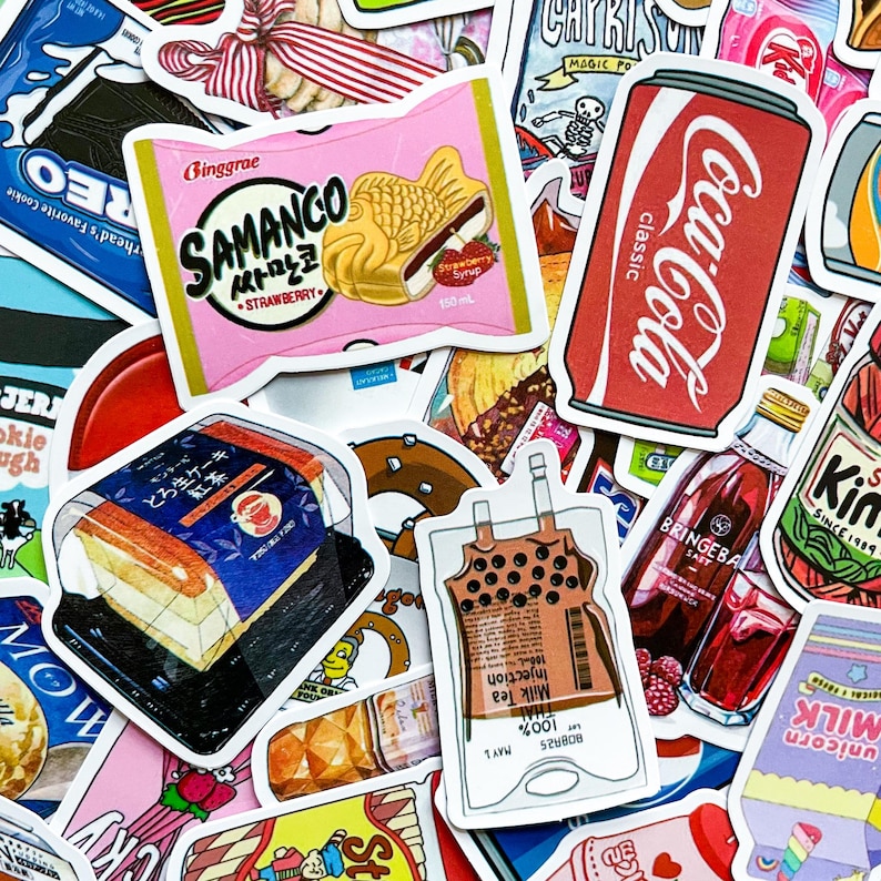 May include: A collection of colorful stickers featuring various food and beverage items. Notable stickers include a pink package of Samanco strawberry ice cream, a Coca-Cola can, and a package of Japanese cake.