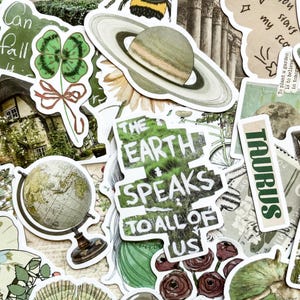May include: A collection of decorative stickers with various designs. Includes a globe, a Saturn-like planet, a four-leaf clover, and text that reads "The Earth Speaks to All of Us" and "Taurus". The stickers are in shades of green, brown, and white.