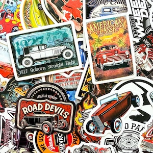Könnte beinhalten: Eine Sammlung von Aufklebern zum Thema Oldtimer. Abgebildet sind Aufkleber mit klassischen Autoillustrationen, darunter ein 1927 Auburn Straight Eight, ein 1947 Ford und ein Road Devils-Design. Die Aufkleber haben einen Retro-Look.