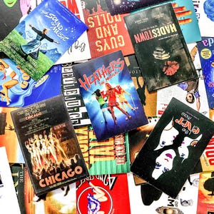 May include: A selection of vintage musical theatre playbills, including "The Sound of Music," "Chicago," and "Hadestown." The covers display colourful illustrations and text, showcasing various show titles and cast members. The playbills are arranged in a scattered, overlapping pattern.