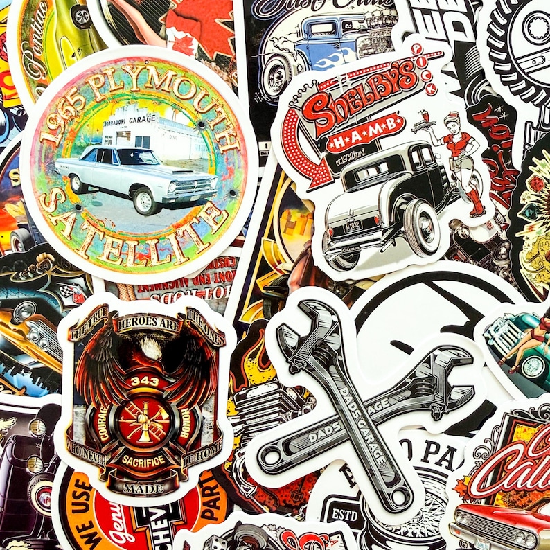 May include: A collection of vintage-style stickers featuring classic cars, garage themes, and automotive-related graphics. Includes a 1965 Plymouth Satellite sticker, a "Shelby's" sticker, and crossed wrench stickers. The stickers have a distressed, retro aesthetic.