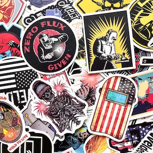 May include: A collection of stickers featuring welding themes. Designs include a welder with the text "Zero Flux Given", a skeleton welding, and an American flag-themed welding mask. The stickers are in various shapes and sizes.