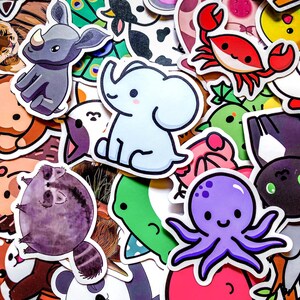May include: A collection of colorful animal stickers, including a light blue elephant, a purple octopus, a red crab, and a gray rhino. Other stickers feature a raccoon, a cow, and a panda. The stickers have a cartoon style and are suitable for various crafts and projects.