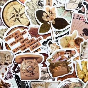 May include: A collection of vintage-themed stickers featuring a compass rose, playing cards, a rotary phone, and botanical illustrations. One sticker has the text: "She's an old soul with young eyes, a vintage heart, and a beautiful mind."
