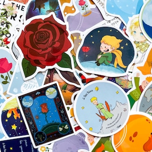 Peut inclure: Une collection d'autocollants colorés avec des illustrations du "Petit Prince". Les motifs incluent une grande rose rouge, le personnage du Petit Prince et des scènes avec des étoiles et des planètes. Les autocollants ont une finition brillante et des formes variées.