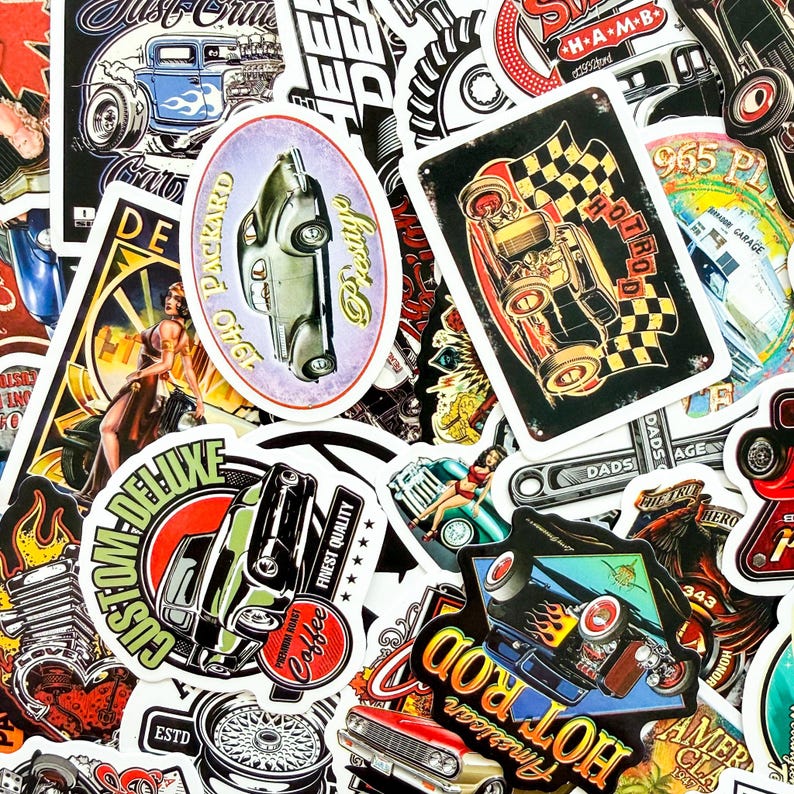 May include: A collection of vintage-style stickers featuring classic cars, hot rods, and automotive-themed designs. The stickers showcase various colors, including red, black, and blue, with text such as "American Hot Rod" and "Custom Deluxe".