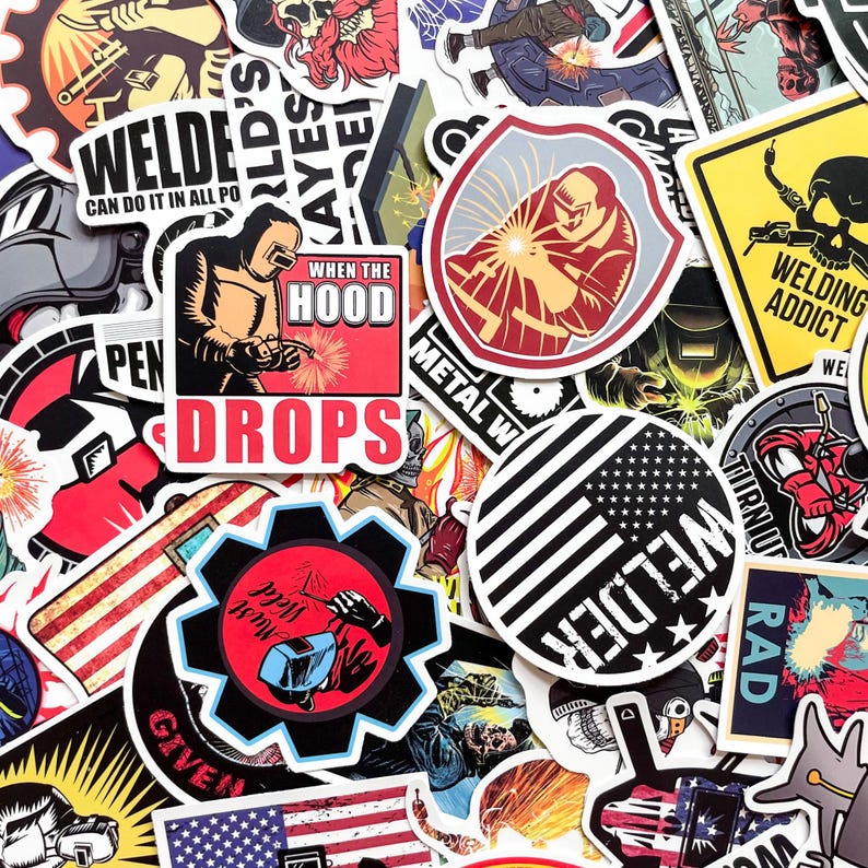 May include: A collection of colorful stickers with welding-themed designs. The stickers feature images of welders, welding tools, and text like "Welder" and "When the Hood Drops." The stickers are in various shapes and sizes.