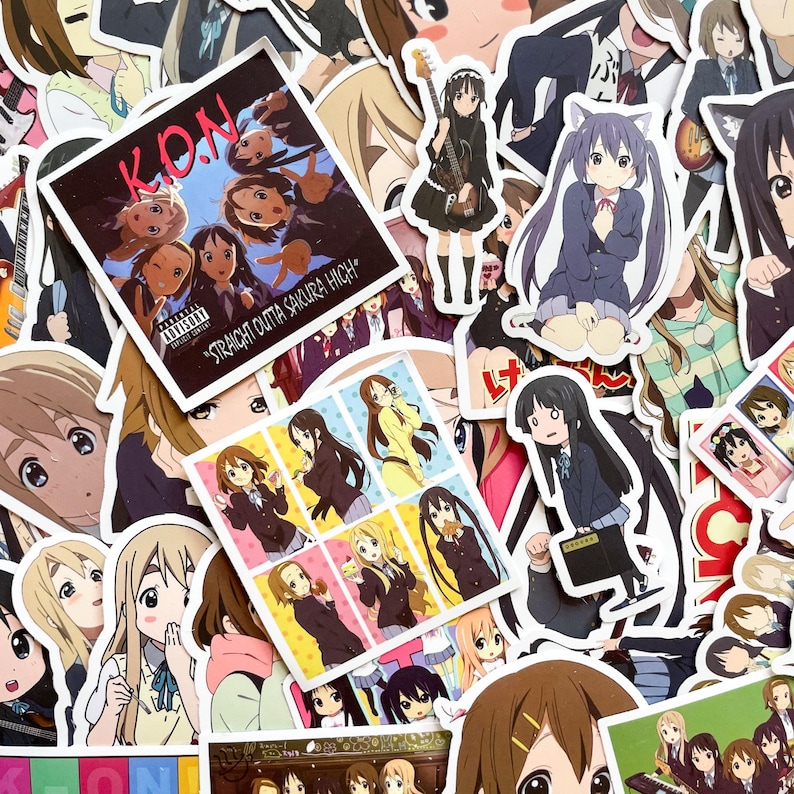 Pode incluir: Uma cole&ccedil;&atilde;o de autocolantes em estilo anime com v&aacute;rios personagens e designs. Alguns autocolantes incluem texto como "K.O.N" e "Straight Outta Sakura High". Os autocolantes exibem uma variedade de cores e poses, com foco na arte em estilo mang&aacute;.